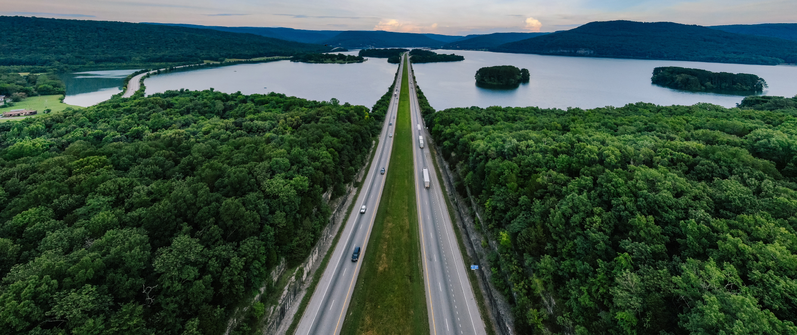 Motorväg bland träd och sjö mot horisonten